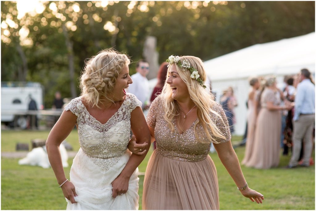 Bride and bridesmaid laughing on wedding day