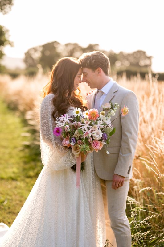 Bride and groom standing in field at their wedding at Titchfield Barn